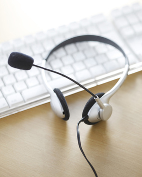 Image d'écouteurs sur un clavier blanc illustrant les services de rédaction de comptes rendus pour organismes publics