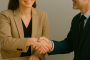 Deux professionnels se serrent la main avec le sourire lors d’une rencontre de travail, symbole de collaboration réussie et de confiance mutuelle.