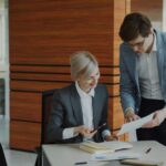 Manager remettant un document à une collaboratrice dans un bureau, symbole de la délégation en entreprise.