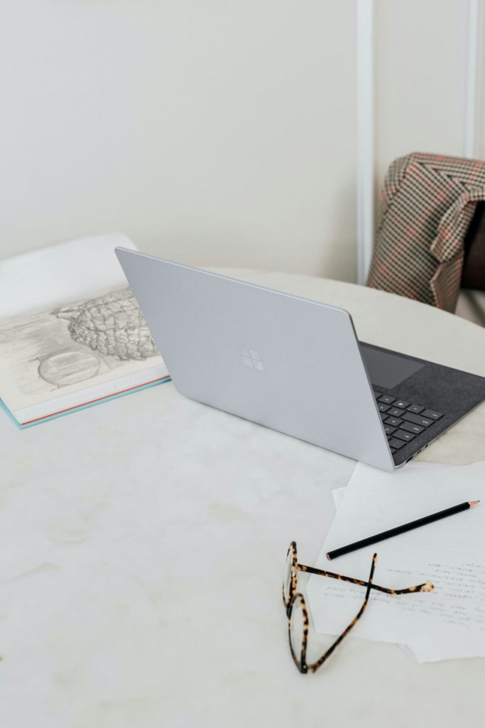 Ordinateur portable sur un bureau clair avec carnet, crayon et lunettes, illustrant la réflexion et la clarté derrière un contenu qui inspire confiance.