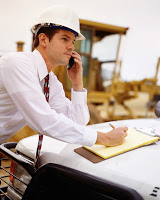 dirigeant sur un chantier portant un casque qui est au téléphone et prend des notes