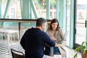 Un homme et une femme échangeant autour d'une table de travail illustrant les dirigeants de TPE-PME